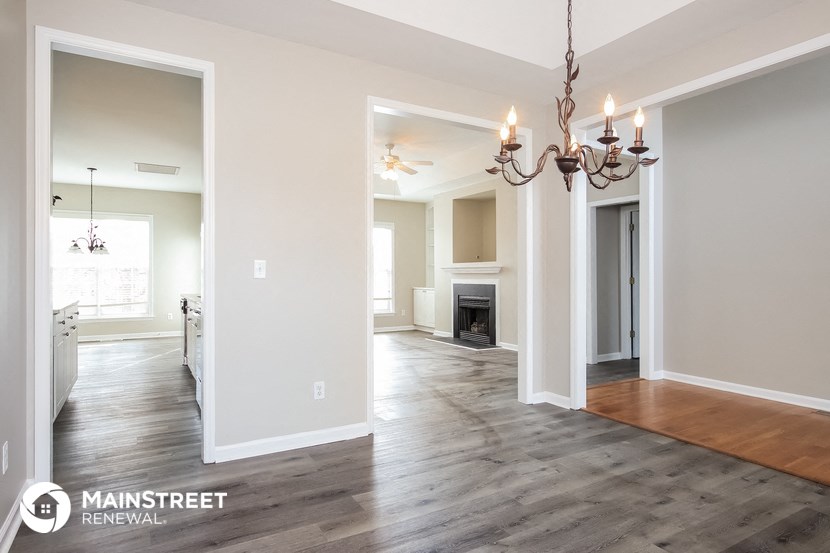 a renovated living room and dining room with wood floors and a chandelier
