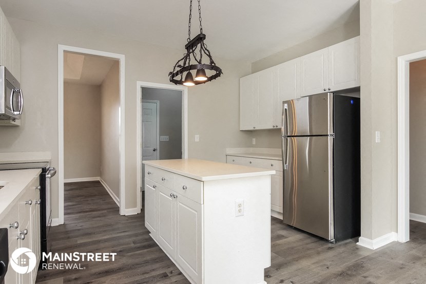 a kitchen with white cabinets and a stainless steel refrigerator
