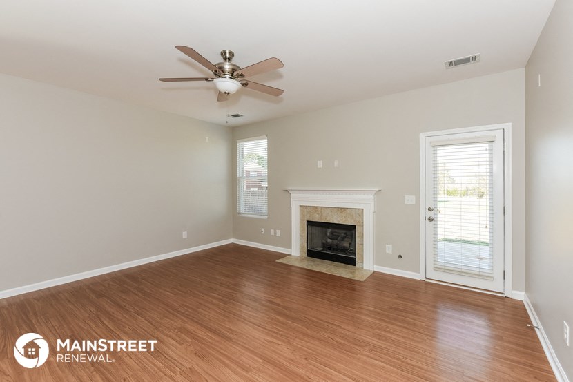 an empty living room with a ceiling fan and a fireplace
