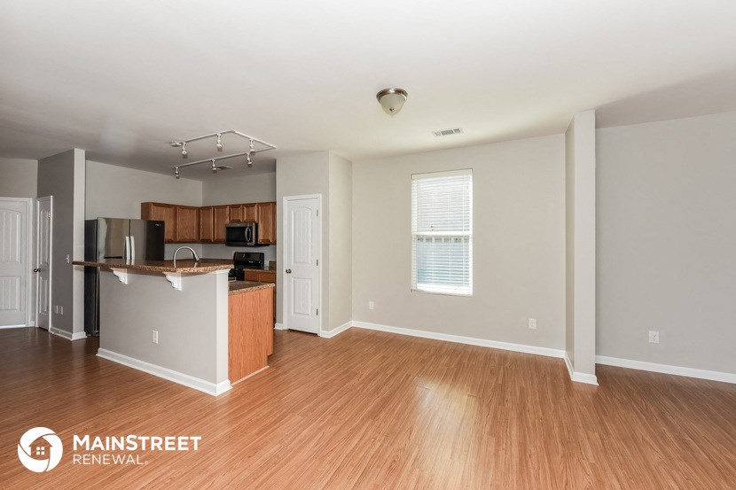 an empty living room and kitchen with wood flooring