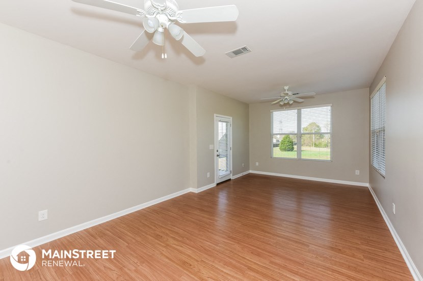 an empty living room with wood flooring and a ceiling fan