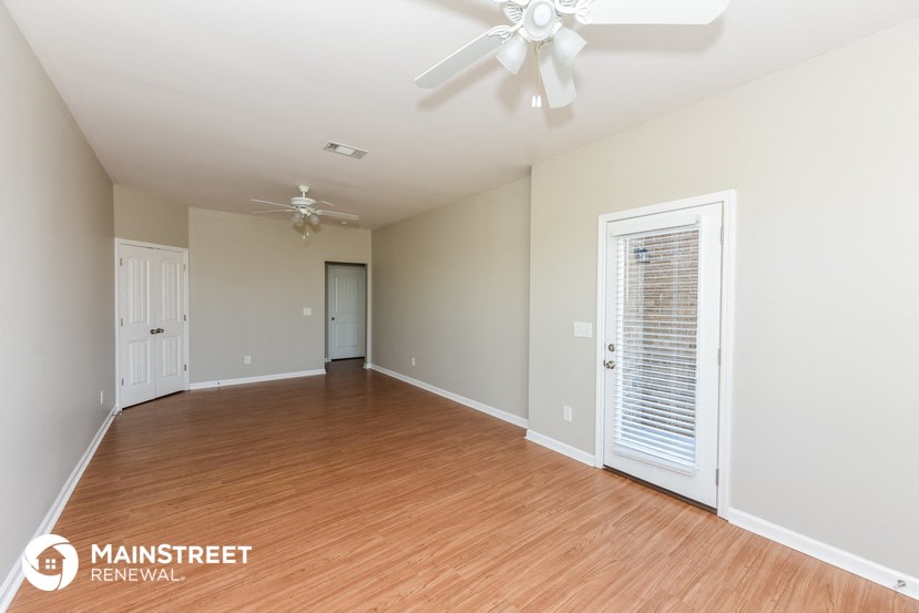 a spacious living room with wood flooring and a ceiling fan