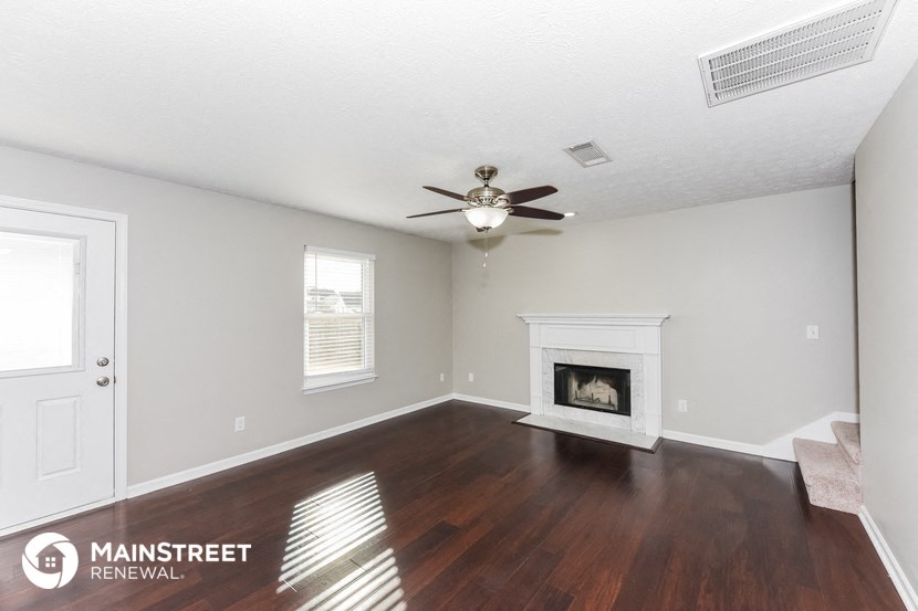a living room with a fireplace and a ceiling fan