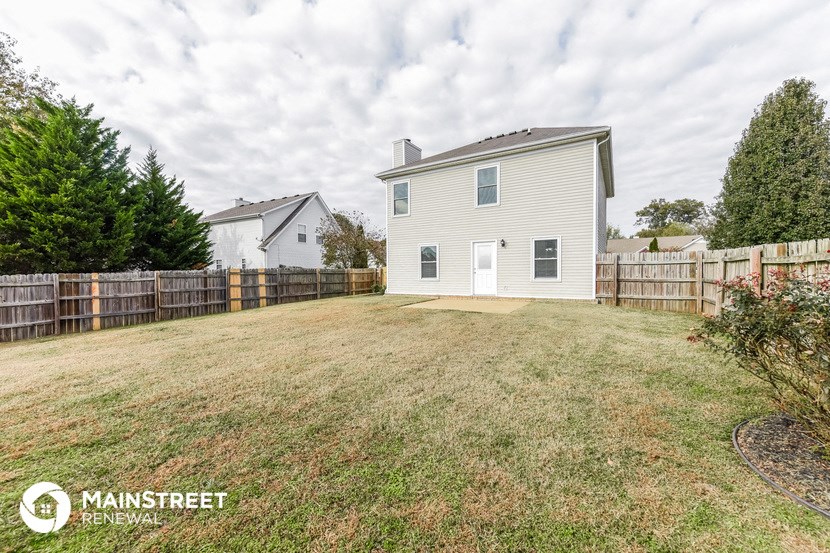 a fenced backyard with a house and a fence