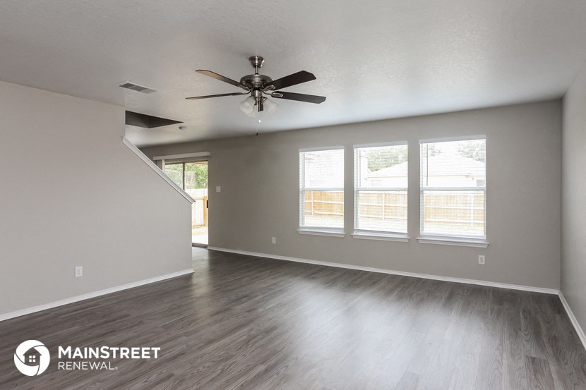 the living room of an empty house with a ceiling fan