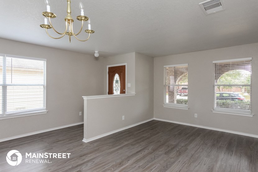 an empty living room with a chandelier and windows