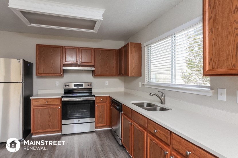 a kitchen with wooden cabinets and white counter tops and a black stove and refrigerator