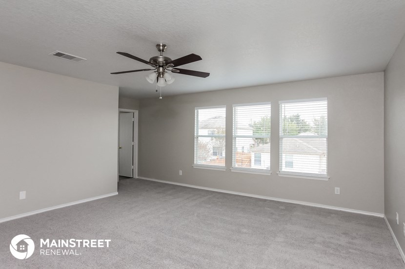 the living room of an empty house with a ceiling fan
