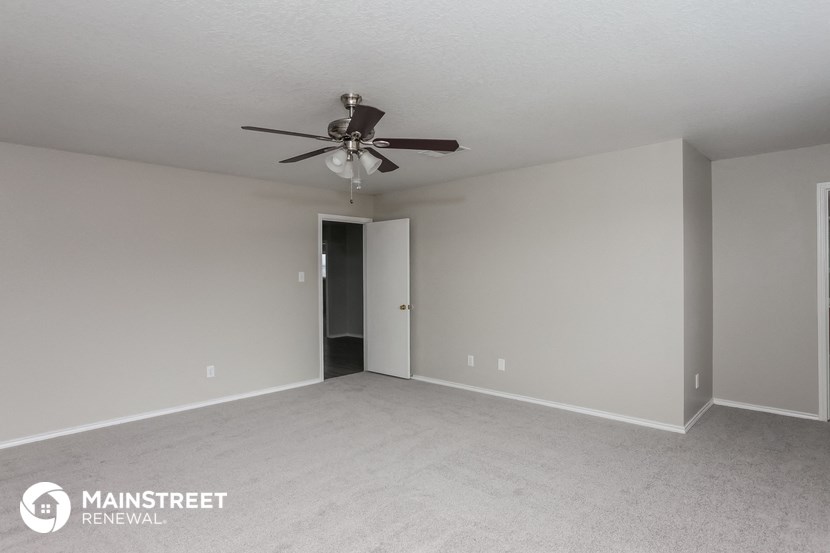 an empty living room with a ceiling fan