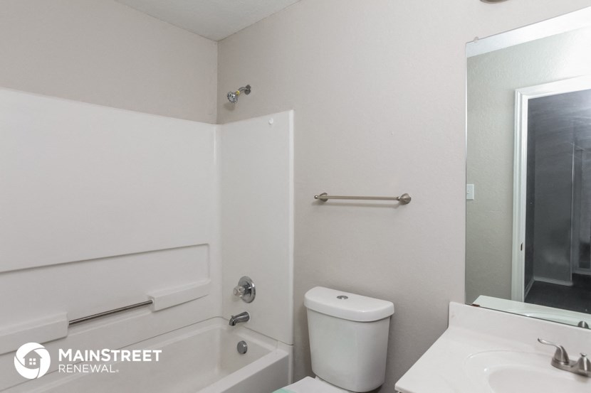 a white bathroom with a white toilet and a bath tub
