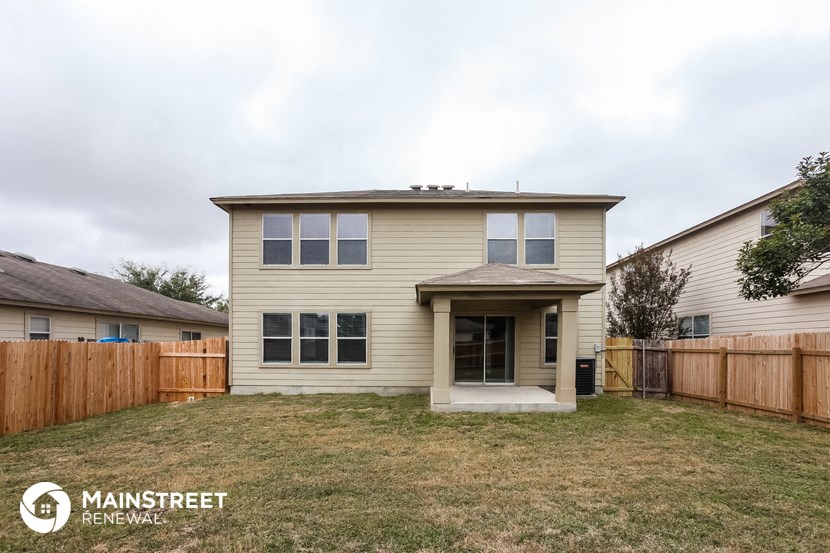 a tan house with a fenced in yard and a wooden fence