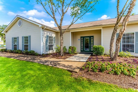 A house with a green lawn and a tree in front.