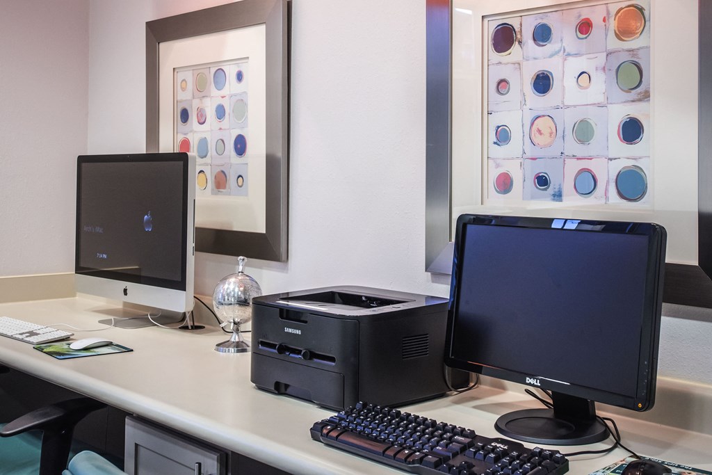 a desk with two computer monitors and a printer on it