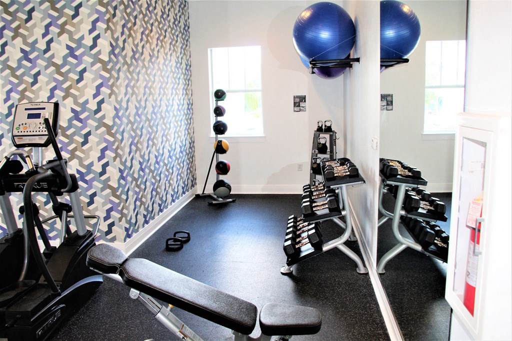 a gym with treadmills and weights in a room with a blue ball