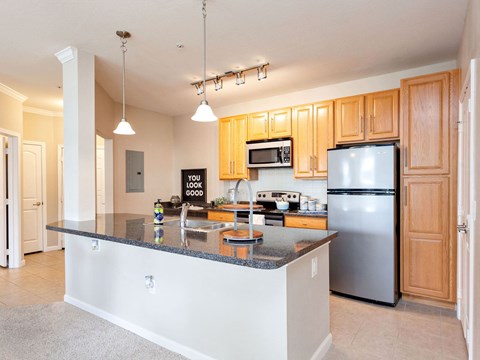 a kitchen with a large island and a stainless steel refrigerator