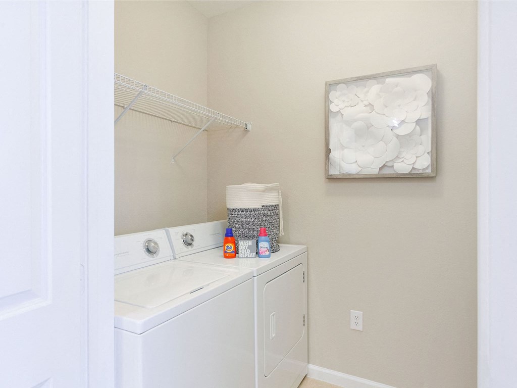 a white washer and dryer in a small laundry room with a white sink