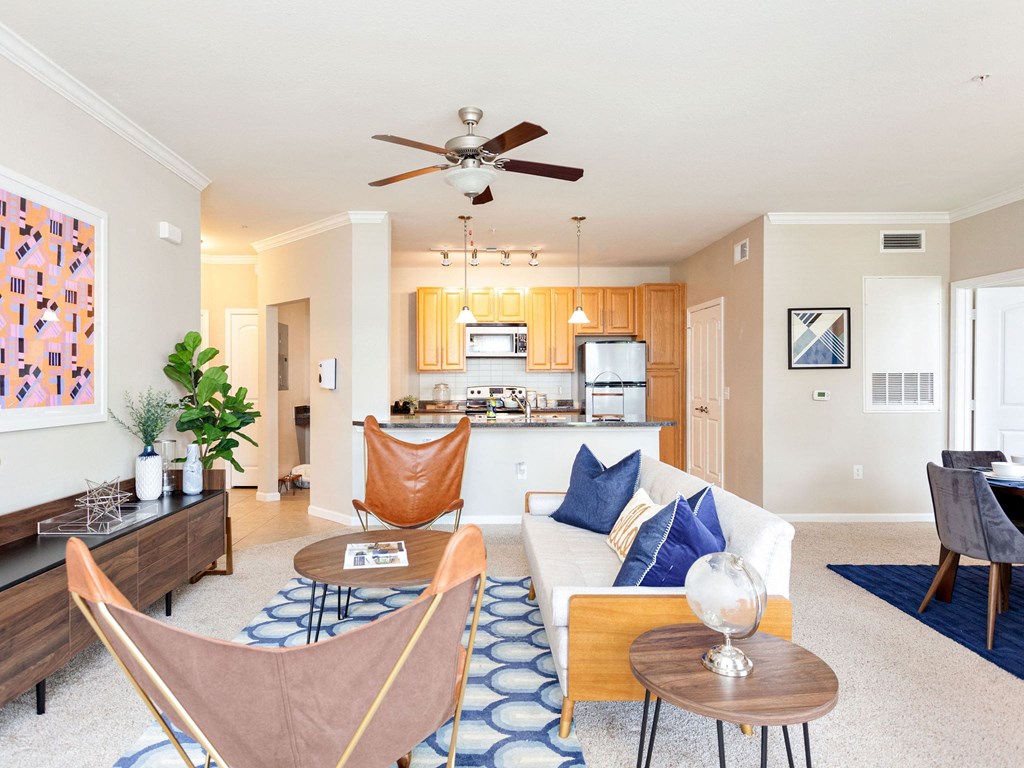 a living room with furniture and a kitchen in the background
