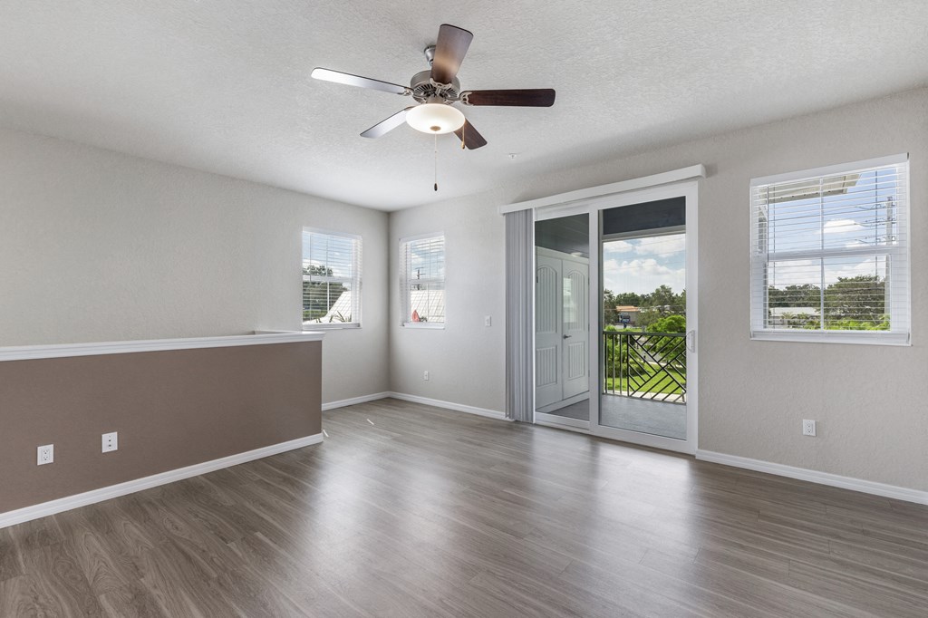 an empty living room with a ceiling fan