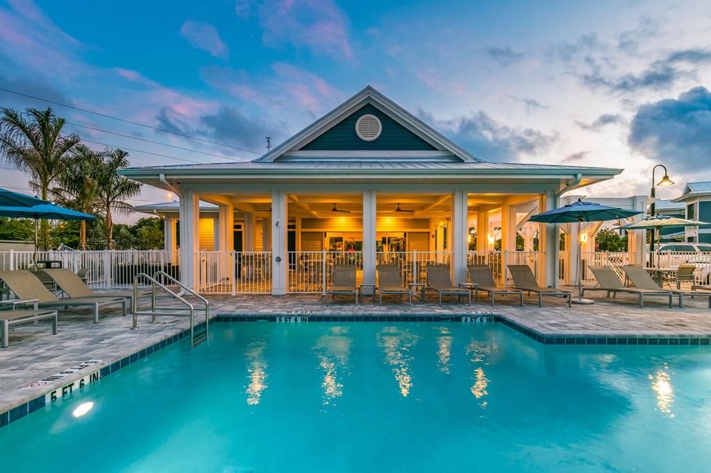 a pool with chairs and a building with a covered porch