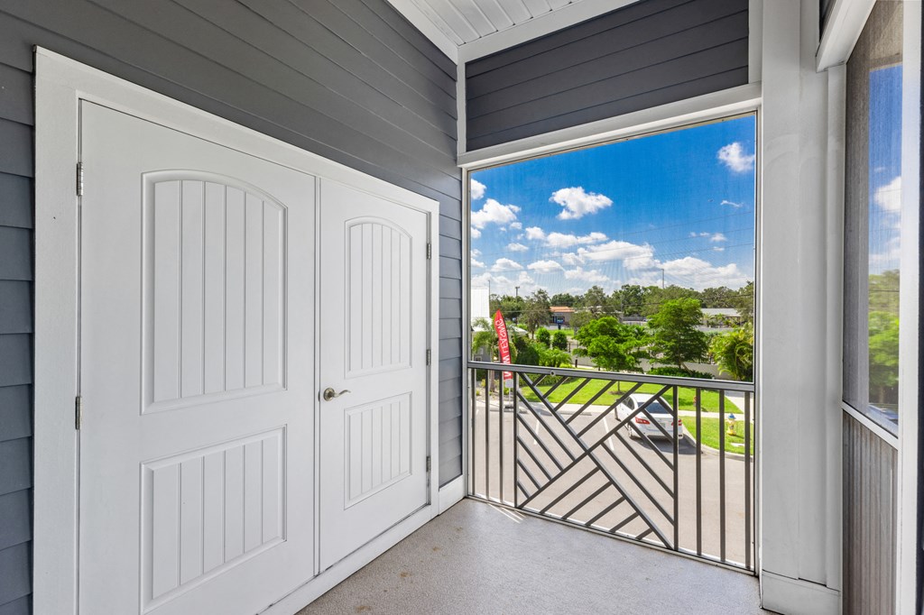 a white door opens to a balcony with a view of the city