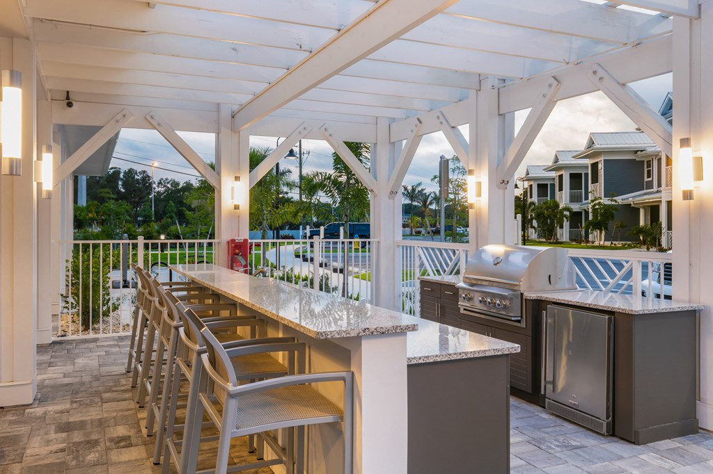 a covered outdoor kitchen with stainless steel appliances and bar stools