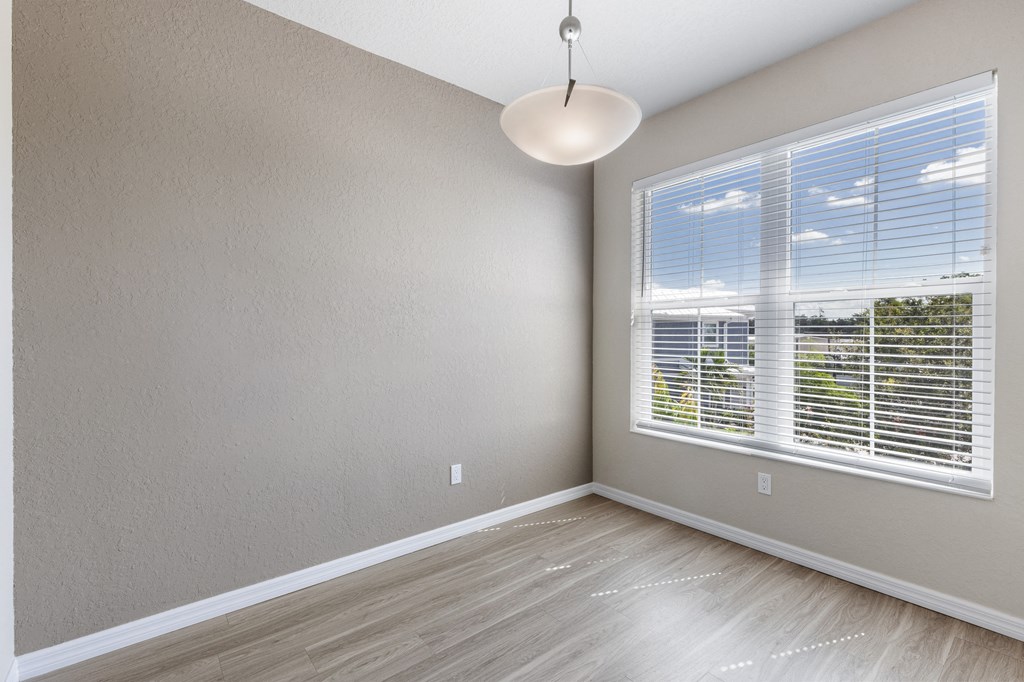 an empty room with a large window and wood floors
