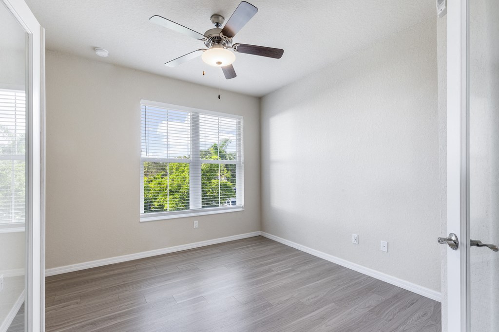 an empty living room with a ceiling fan and a window