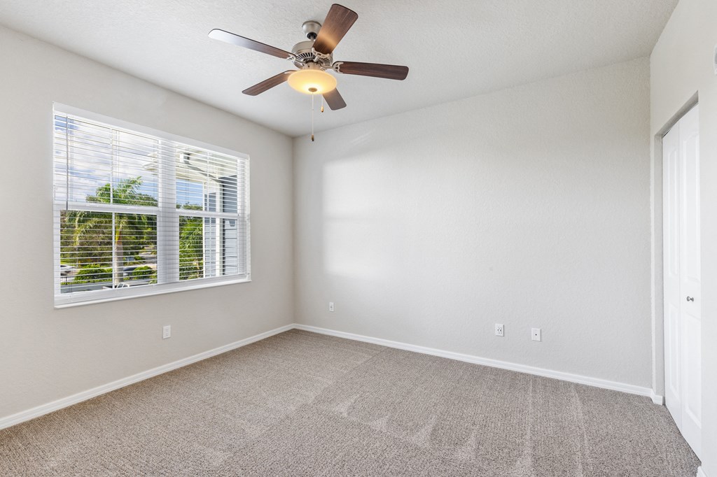 an empty living room with a ceiling fan and a window