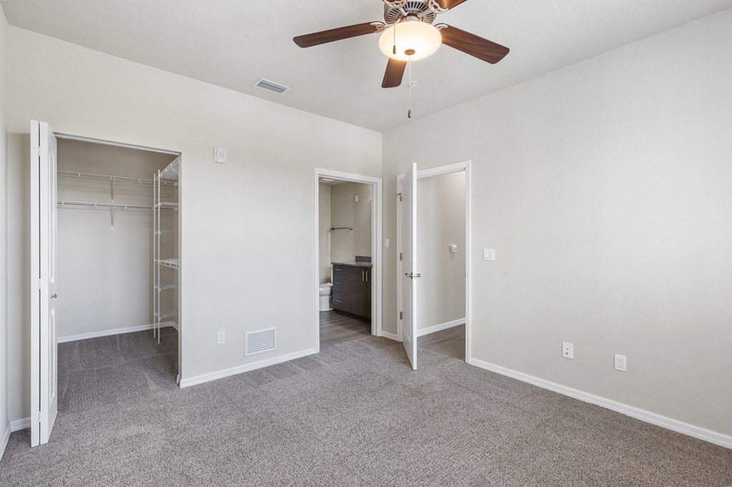 an empty bedroom with a ceiling fan and a closet