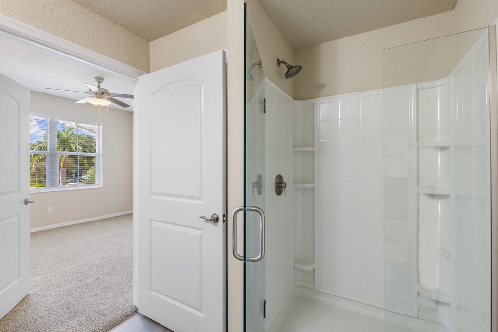 an empty bathroom with a shower and a ceiling fan