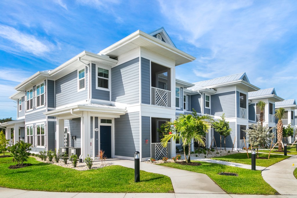 a row of blue and white houses with a sidewalk and grass