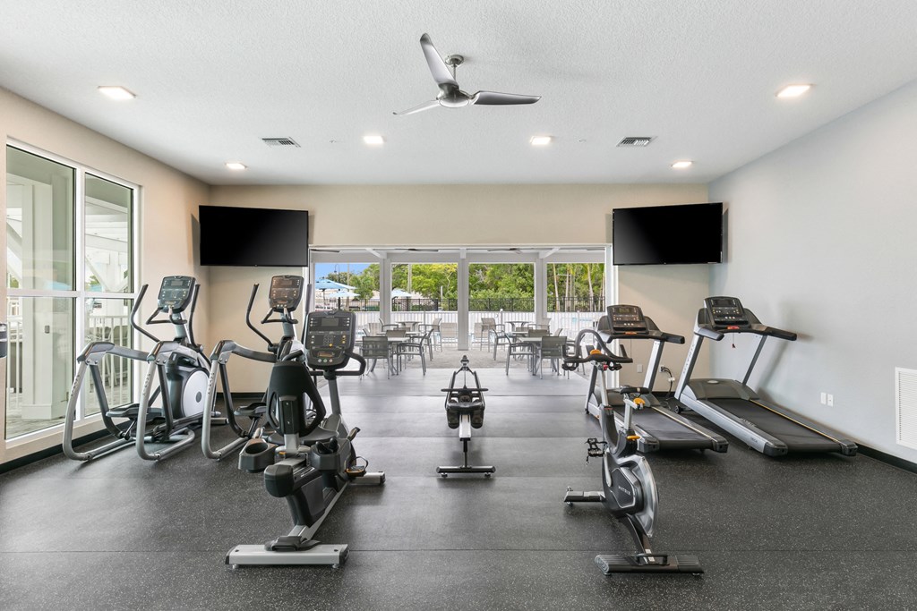 the gym has plenty of cardio equipment and glass doors to the patio