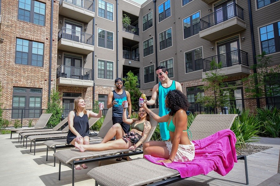 a group of people sitting on chaise lounge chairs in front of an apartment building