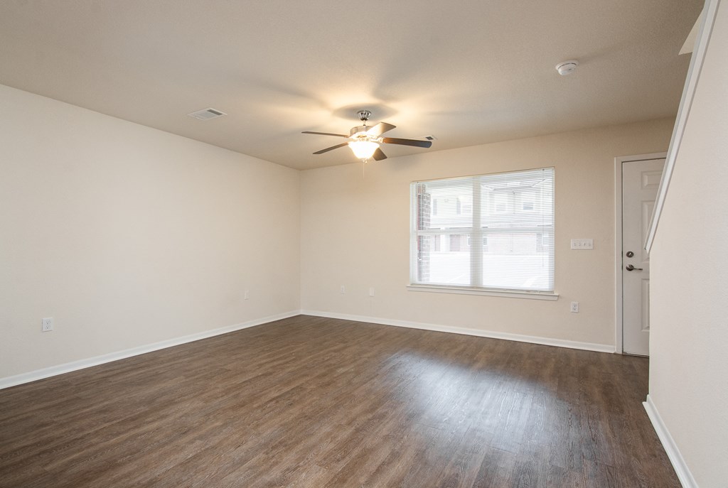 an empty living room with a ceiling fan and a window