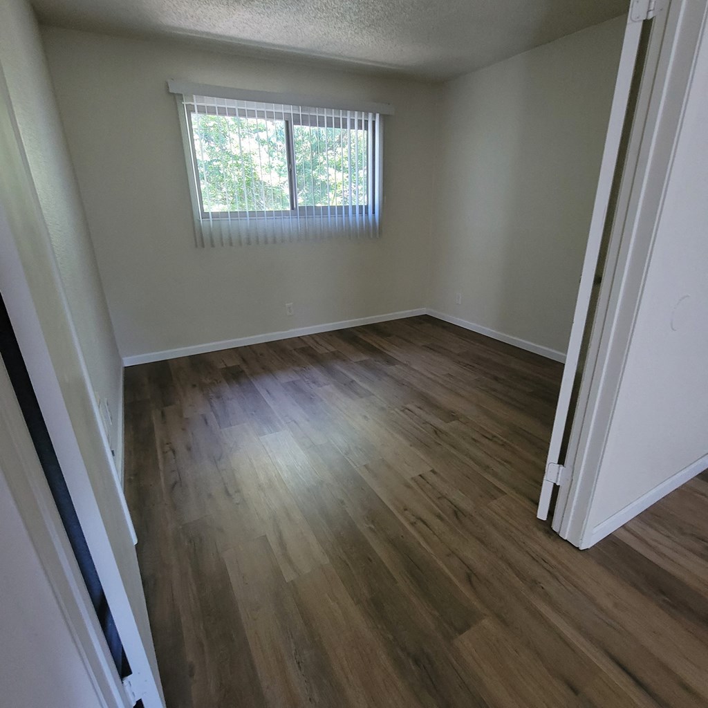 an empty living room with wooden floors and a window