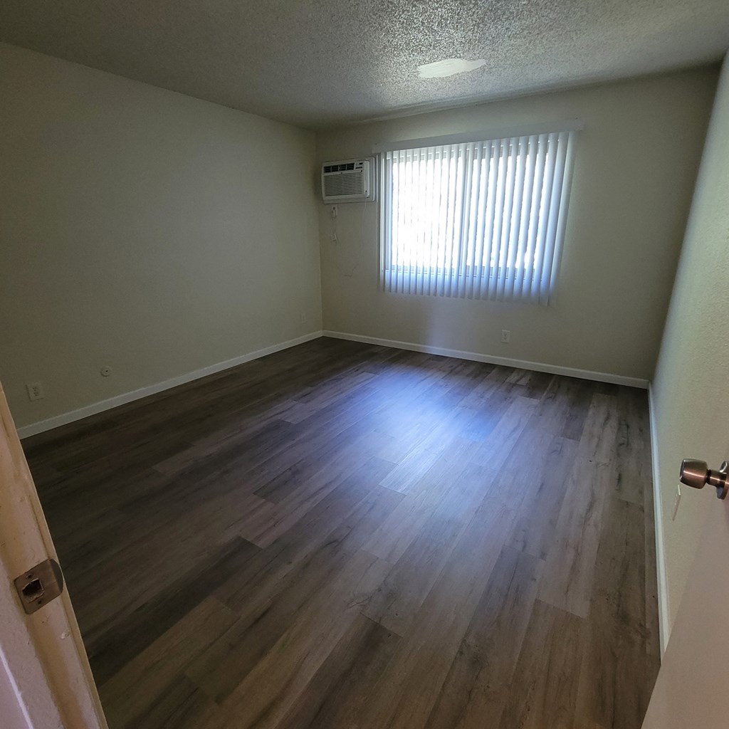 an empty living room with wooden floors and a window