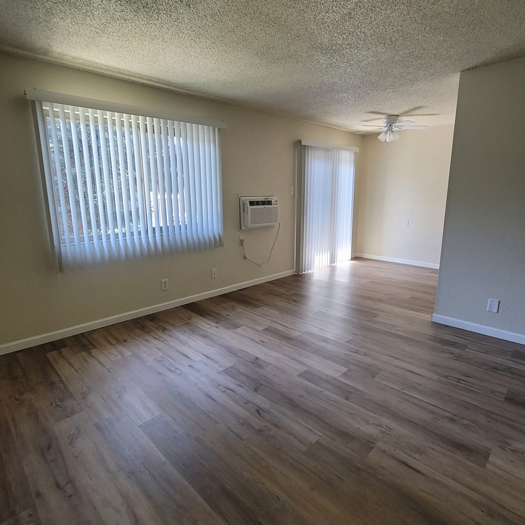 an empty living room with wooden floors and a window