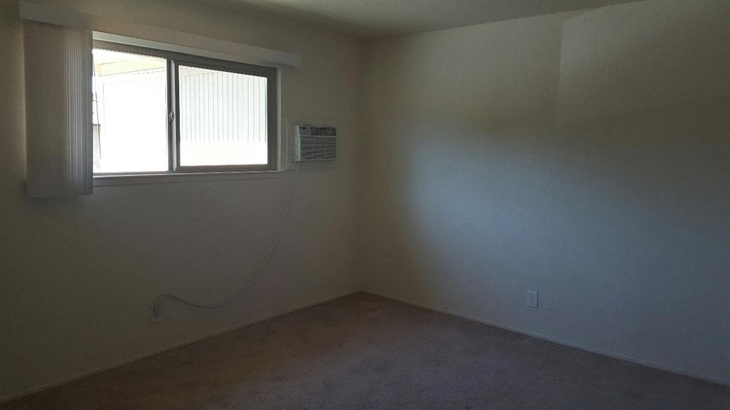 an empty room with a window and an air conditioner