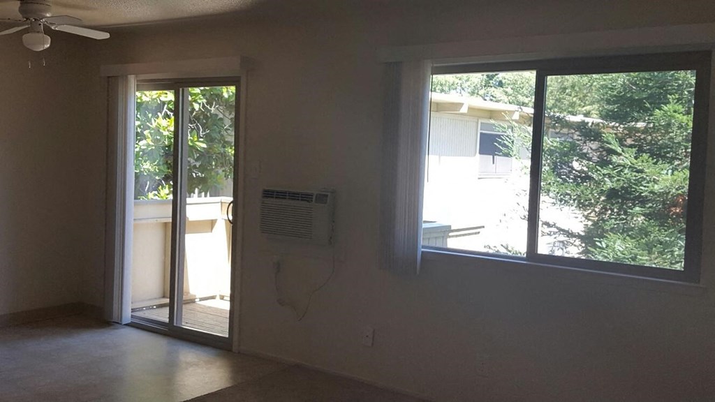 an empty living room with a window and a air conditioner