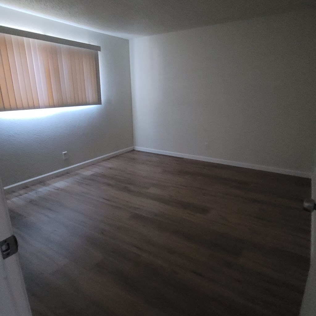 an empty room with wooden floors and a window