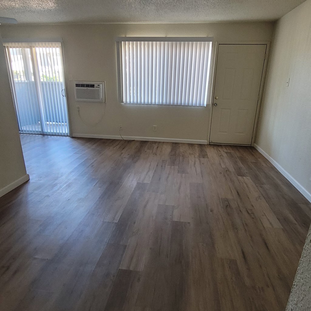 an empty living room with wooden floors and a window