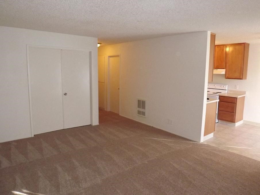 an empty living room with a kitchen in it