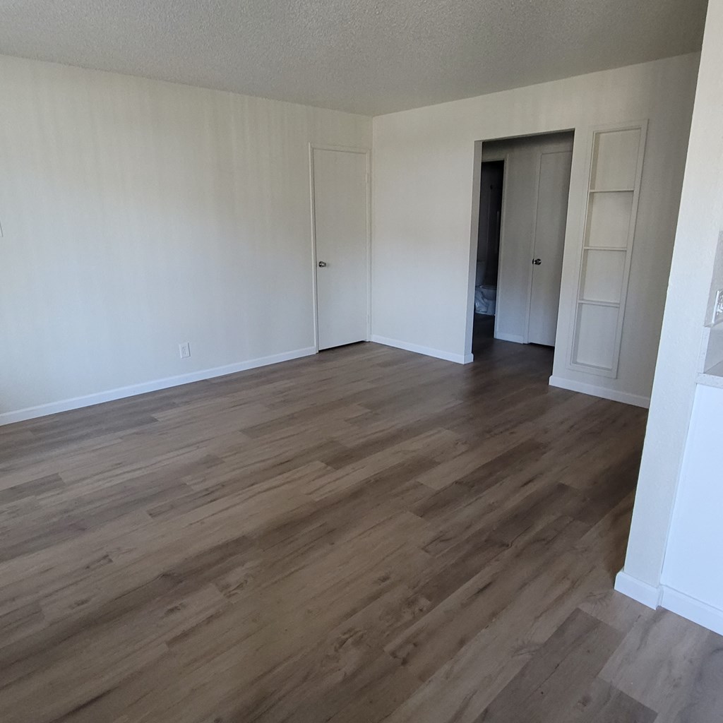 an empty living room with wooden floors and white walls