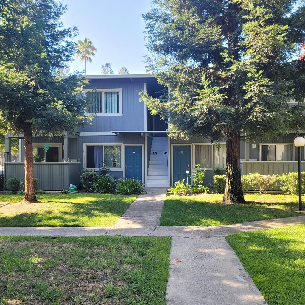 a blue house with a sidewalk and trees in front of it
