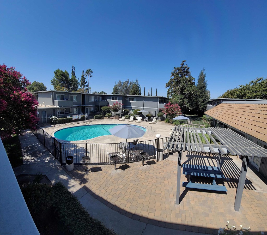an aerial view of a pool and patio with picnic tables