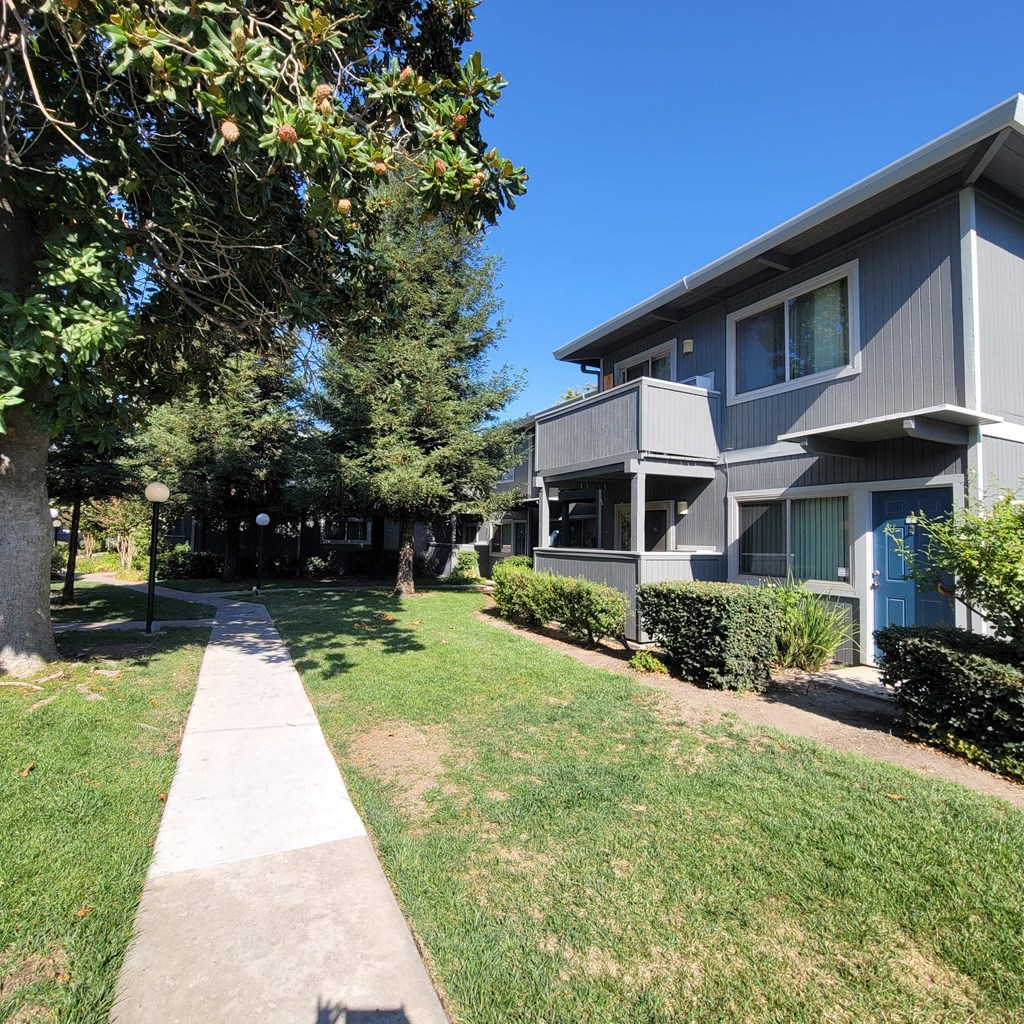 the view of an apartment building with a sidewalk in front of it