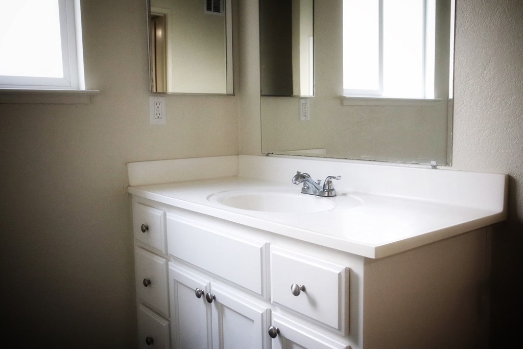 A white bathroom sink with a silver faucet and a mirror above it.