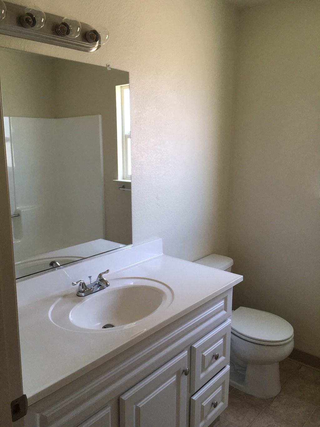 A white bathroom with a toilet, sink and mirror.