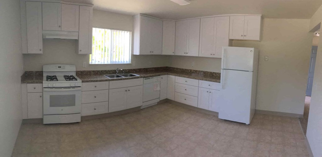 A kitchen with white cabinets and appliances.
