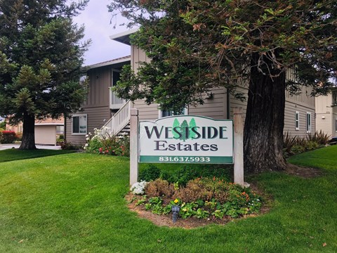 A sign for Wes Side Estates in front of a building.